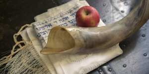 A ram’s horn,or shofar;a Jewish prayer shawl,or talit;and an apple symbolise Rosh Hashanah.