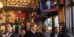 People sit in the Red Lion pub as former prime minister Boris Johnson giving evidence on partygate is shown on the TV.