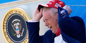 Brace yourself for the tariff storm:President Donald Trump holds his MAGA hat in the wind while disembarking Air Force One last month.