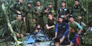 In this photo released by Colombia’s Armed Forces Press Office,soldiers and Indigenous men pose for a photo with the four Indigenous children who were missing after a deadly plane crash.