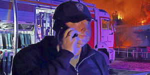 Sevastopol Governor Mikhail Razvozhaev speaks on the phone as smoke and flames rise from Sevastopol Shipyard in Crimea.