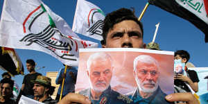 A supporter of an Iran-backed militia holds a poster of slain Iranian General Qassem Soleimani,left,and deputy commander Abu Mahdi al-Muhandis during a protest by pro-Iranian militiamen in Iraq.