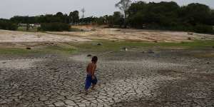 A boy walks across a dry,cracked area of the Negro River near his houseboat in Manaus. The river reached its lowest level in more than 120 years on Monday.