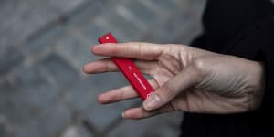 A woman holds a flavoured disposable vape device.