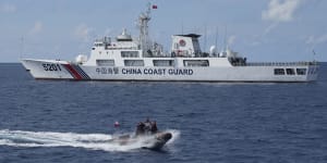 The crew of Philippine Coast Guard patrol vessel BRP Malabrigo rides a motor boat past China Coast Guard ship.