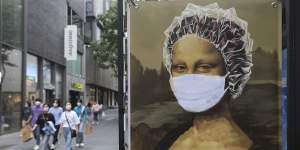 People wearing face masks to help protect against the spread of the new coronavirus walk by an advertisement of a hair shop at a shopping district in Seoul,South Korea,Tuesday,May 26,2020. (AP Photo/Ahn Young-joon)