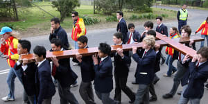 Students from Redfield College march with a cross in Dural.
