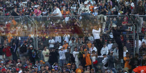 Fans scale a fence and enter the track at Albert Park after the 2023 Grand Prix.