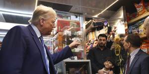 Former president Donald Trump talks with bodega owner Maad Ahmed,centre,during a campaign stop at his New York store on Tuesday. 
