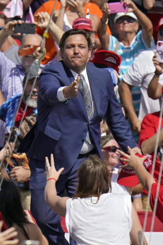 Ron DeSantis, 2020'de dönemin başkanı Donald Trump tarafından düzenlenen bir kampanya mitinginden önce kalabalığa şapka atıyor.