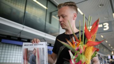 Dutchman Arthur Laumann holds a floral tribute and photograph of family friend Wayan Sujana of Bali, believed to be missing on Malaysia Airlines flight MH17 at Schiphol Airport in Amsterdam, Netherlands. Malaysia Airlines flight MH17 was ravelling from Amsterdam to Kuala Lumpur.