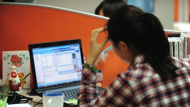 A woman works online in her cubicle at an office in Beijing.