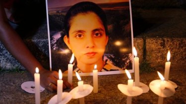 A student of a nursing college places a candle in front of a picture of nurse Jacintha Saldanha.