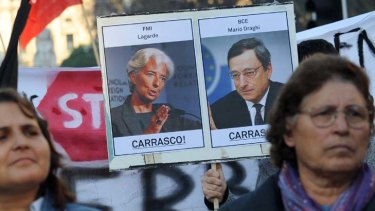 Sceptical ... a man holds a poster depicting Christine Lagarde, head of the International Monetary Fund, and Mario Draghi, President of the European Central Bank, during a demonstration in Porto, Portugal.