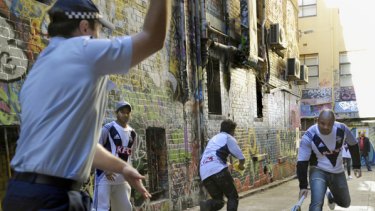 Police and Indian students play a game of laneway cricket in the CBD yesterday.