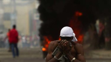 Out of control ... A supporter of presidential candidate Michel Martelly covers his mouth from tear gas thrown by the United Nations peacekeepers during protests in Port-au-Prince.