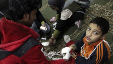 Wounded ... a doctor treats a child at a makeshift casualty ward in a Cairo mosque. There has been widespread use of live ammunition against demonstrators.