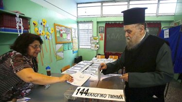 A Greek Orthodox priest casts his ballot at an Athens primary school used as a polling station.