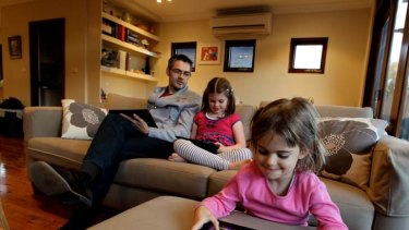 Keep talking ... Andrew Sidwell and his daughters - Hudson, 7, and Lola, 4, using tablets at their home in Maroubra.