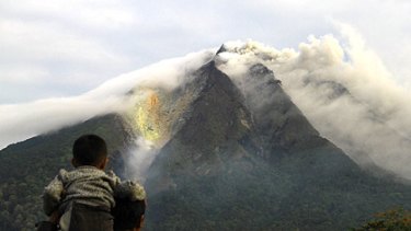 A man and his son watch the smoking volcano yesterday. Many trees near the mountain top were set alight.