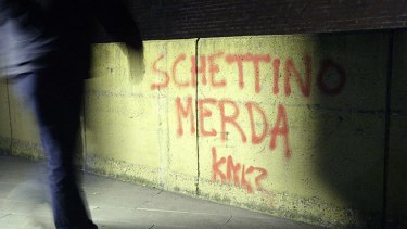 A man walks past a wall sprayed with the  words 'Schettino shit' in front of the prison in Grosseto, where the Italian skipper was being held until today.