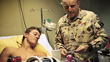 Man down … visiting a wounded soldier, Sapper Michael Clark, in Afghanistan in 2010.