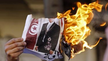 A Tunisian in France burns a picture of Mr Ben Ali.