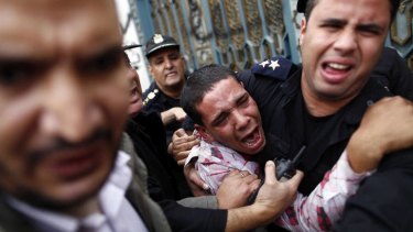 Policemen protect an opposition demonstrator after a scuffle with Morsi supporters in Cairo.