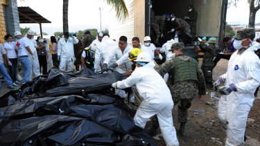 Honduran forensic workers and soldiers remove corpses in plastic bags from the National Prison in Comayagua.