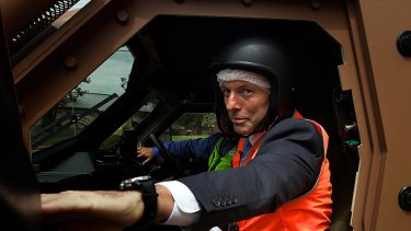 (Legal) action man ...Opposition Leader Tony Abbott tries out a new model 'Hawkaei' all terrain military vehicle at the Thales factory in Bendigo.