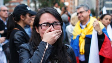 A supporter of the peace accord cries as she follows the results of the referendum on an outdoor TV screen in Bogota, Colombia.