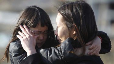 Living a nightmare ... Wakana Kumagai, seven, and her mother Yoshiko cry as they visit the spot where their house used to be.