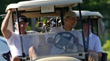 President Barack Obama steers a golf cart with his golfing partner, Vice President Joe Biden