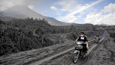 Motorcyclists passing through an area covered by ash as they are evacuated.