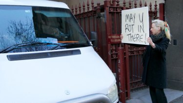 A woman holds up a sign for Adrian Bayley reading 'May you rot in there' as he is driven off to prison.