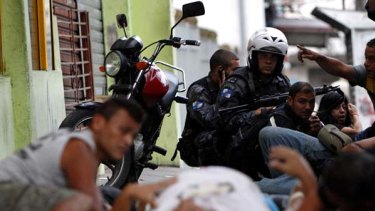 Brazilian police take cover near a resident who was shot during a police operation at the Grota slum in Rio de Janeiro.
