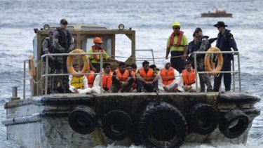Australian customs officials and navy personnel escort asylum seekers onto Christmas Island on August 21, 2013. It has been four months since the last 'successful' people smuggling venture, Immigration Minister Scott Morrison says.