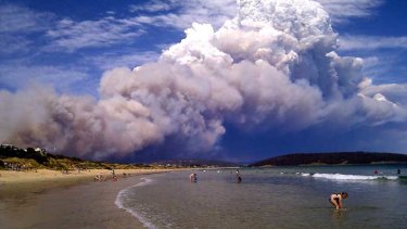 Smoke from a bushfire billows over beach goers at Carlton, about 20 kilometres east of Hobart .