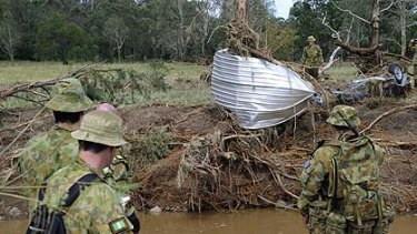 Soldiers from 8th/9th Battalion, Royal Australian Regiment,  search for survivors or victims along Rocky Creek in Postmans Ridge.