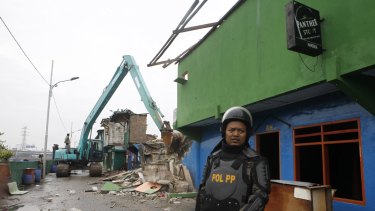 Officers with heavy equipment destroy buildings in Kalijodo after residents and sex workers were evicted.