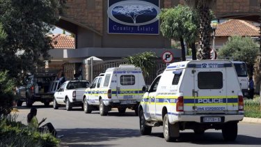Police vehicles enter the private townhouse complex where Oscar Pistorius lives.