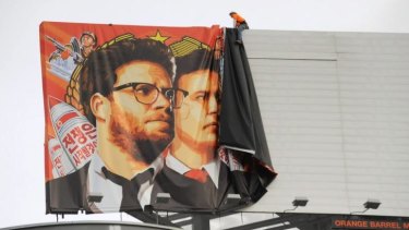 Workers remove a poster for The Interview from a billboard in Hollywood, California, a day after Sony's announcement that it was cancelling the movie's Christmas release.