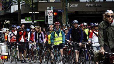 Cyclists walk their bikes past the town hall in Swanston St.