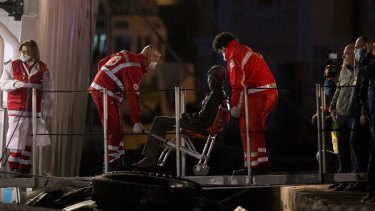 In this April 20 photo, a survivor of the boat that overturned off the coast of Libya disembarks from Italian Coast Guard ship Bruno Gregoretti, at Catania Harbour, Italy. 