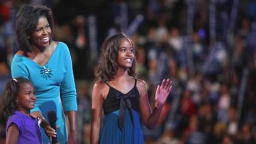 Michelle Obama on stage with daughters Sasha and Malia.