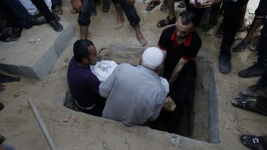 Palestinians lower the body of Muhammed Abu Shagfa, 7, killed in an explosion, into his grave during the funeral in Gaza City.