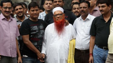 Indian policemen in plain clothes surround Abdul Karim alias Tunda, centre in white cap.