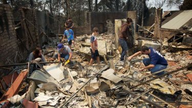 Aftermath of the Winmalee bushfire on Emma Pde. The Kozumplik family sifts through the rubble of what used to be their home for anything that can be salvaged.