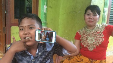 Aldi Rizal, with his mother Diana, quit smoking when he was four. He is 
holding up a YouTube video of his younger smoking self.