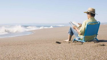 Stock photo of person reading on the beach.